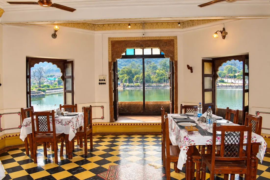 Dining room at Nawal Sagar Palace with carved wooden doors opening onto the lake