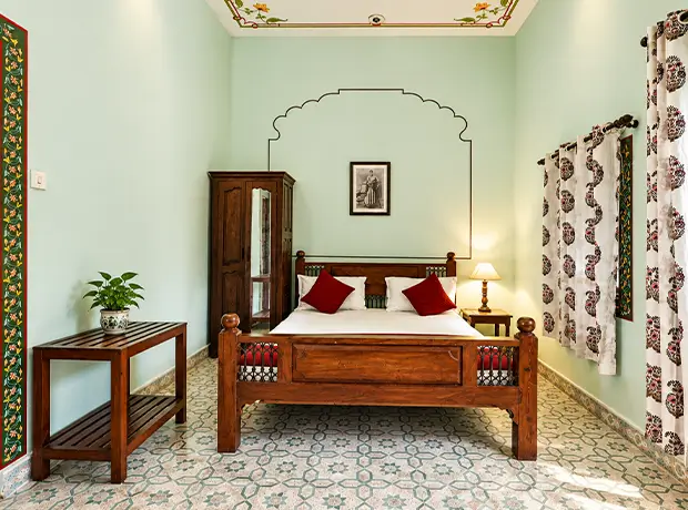 Deluxe Room at Nawal Sagar Palace, mint-walled with a hand-carved wooden bed